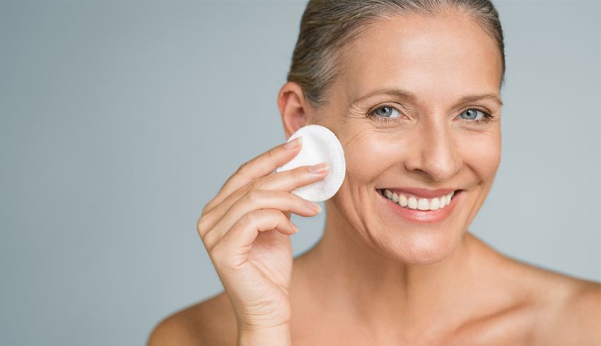 Mature woman pressing cotton round to her right cheek